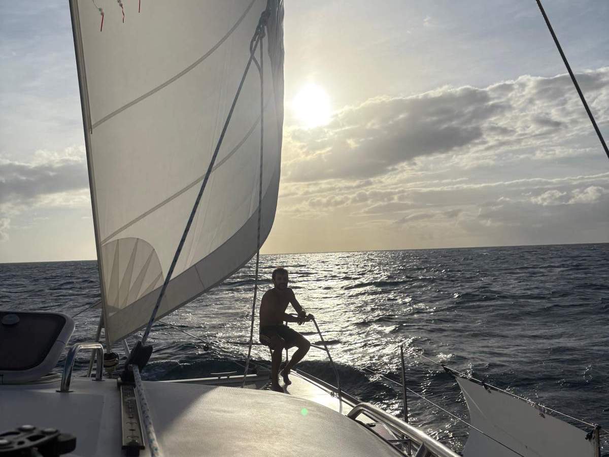 Navigation sous génois au coucher du soleil, un équipier à la proue