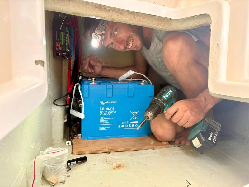 Gaël installe une batterie lithium dans un espace confiné à bord
