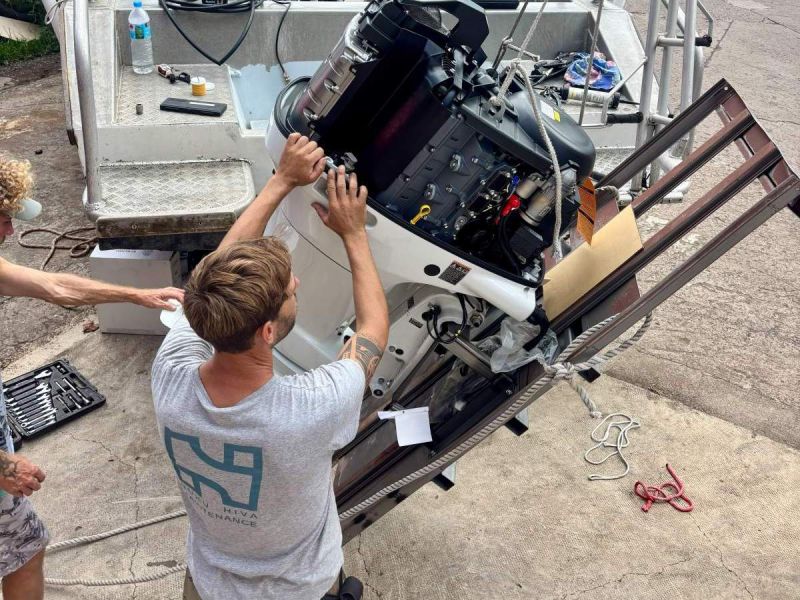 Montage d'un moteur hors-bord sur un bateau de plongée à Taiohae