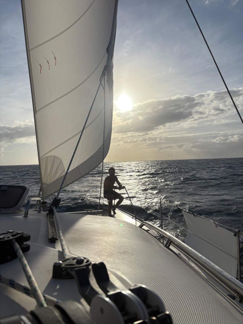 Navigation sous génois au coucher du soleil, un équipier à la proue