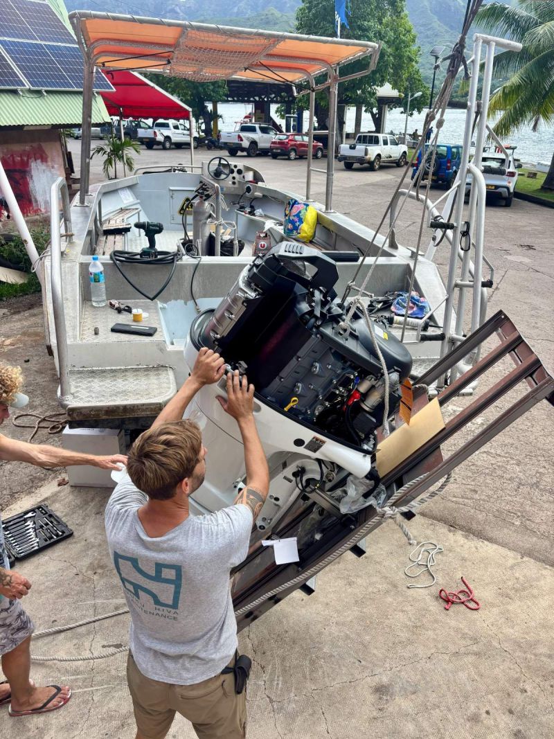 Montage d'un moteur hors-bord sur un bateau de plongée à Taiohae