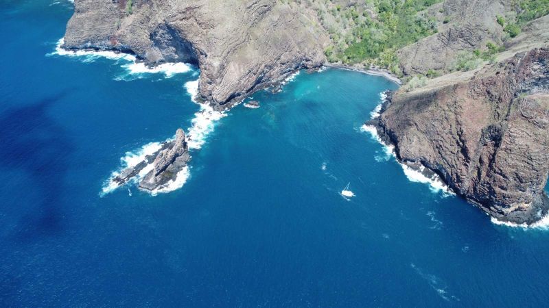 Falaises et baie de Ua Huka, un voilier au mouillage